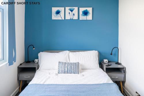 1 dormitorio azul con 1 cama y 2 mesitas de noche en Modern Riverside Place - Principality Stadium - Fast Wifi, en Cardiff
