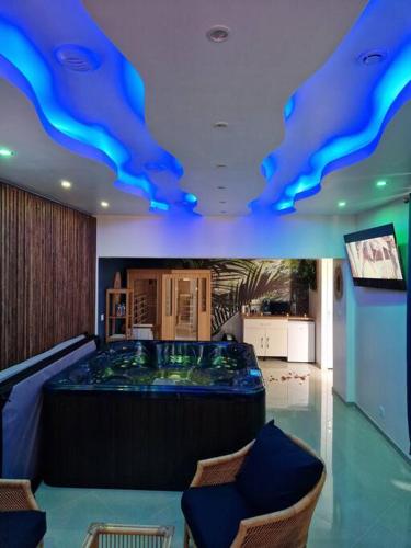 una habitación con un bar con luces azules en el techo en Suite Tropicale avec jacuzzi YaoSpa60, 