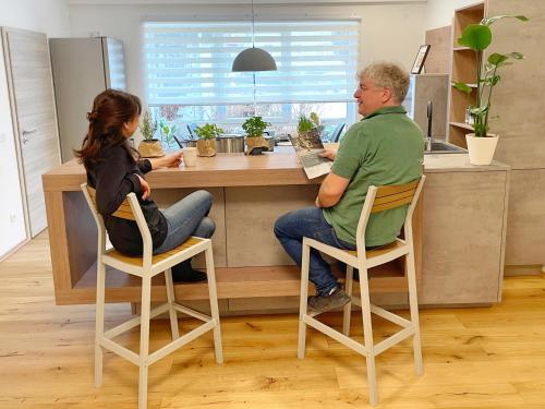 a man and a woman sitting at a counter in a kitchen at Edle neue Ferienwohnungen in der Nähe der Bastei in Stadt Wehlen