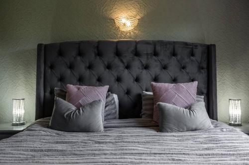 a bed with a black headboard and pillows on it at City home with parking and garden- pet friendly in Chester
