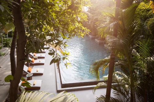 a pool in the middle of a courtyard with palm trees at Plantation Urban Resort & Spa in Phnom Penh