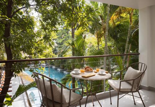 einen Tisch und Stühle auf einem Balkon mit Poolblick in der Unterkunft Plantation Urban Resort & Spa in Phnom Penh