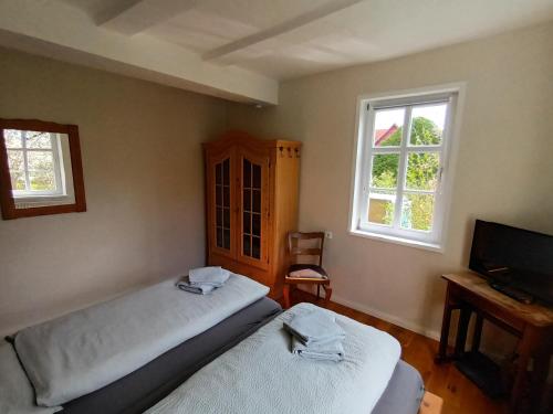 a bedroom with two beds and a tv and two windows at Ferienhaus 1893 Frielendorf in Frielendorf