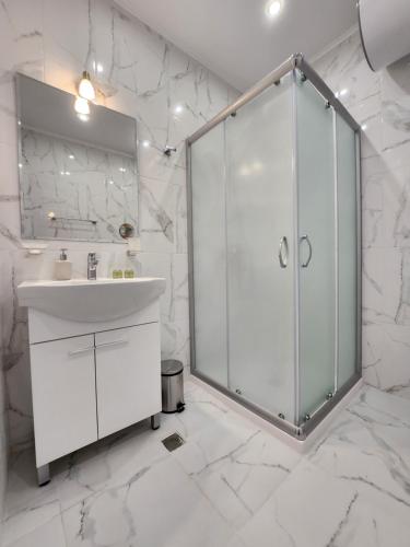 a white bathroom with a shower and a sink at Golden Sands Apartments Zlatna Kotva in Golden Sands