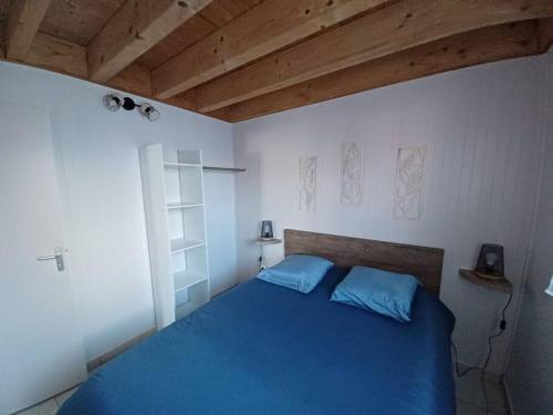 a bedroom with a blue bed with a wooden ceiling at La Maison Bleu du Lac de Céline in Giffaumont