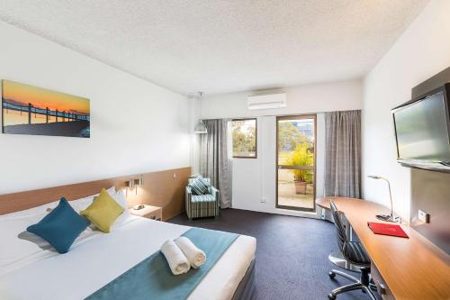 ein Hotelzimmer mit einem Bett und einem Schreibtisch in der Unterkunft Metro Hotel Miranda in Miranda