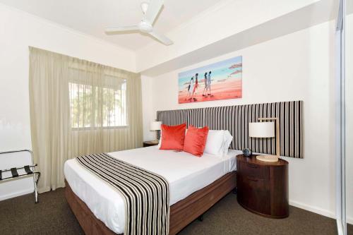 um quarto com uma cama grande e almofadas vermelhas em Metro Advance Apartments & Hotel em Darwin