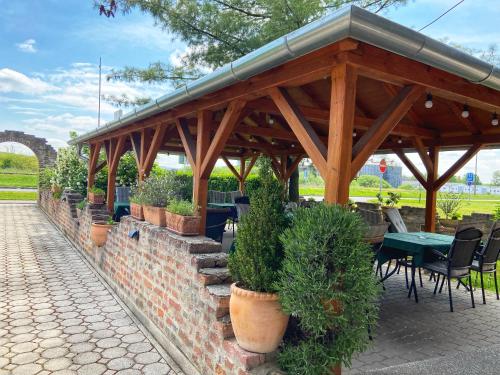 a wooden pavilion with potted plants on a brick wall at Hotel Zéta in Lenti