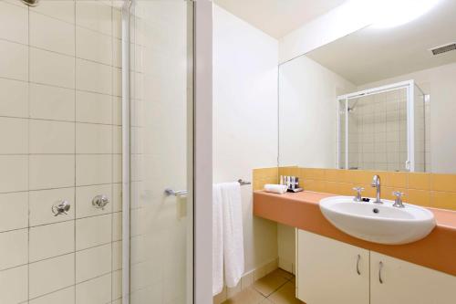 a bathroom with a sink and a shower at Metro Advance Apartments & Hotel in Darwin