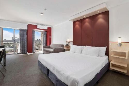 a hotel room with a large bed and a chair at Metro Hotel Perth in Perth