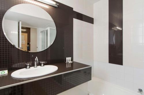 W łazience znajduje się umywalka i lustro. w obiekcie Metro Hotel Perth w mieście Perth