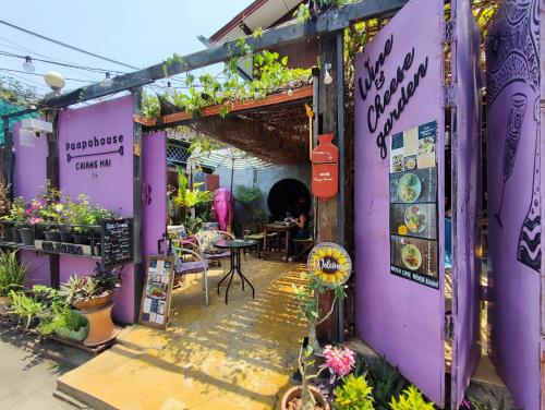 een paars gebouw met een tafel, stoelen en planten bij Paapu House in Chiang Mai