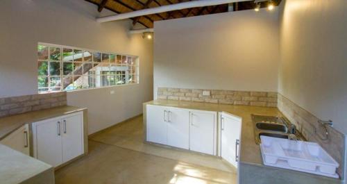 a large kitchen with white cabinets and a sink at Beautiful home overlooking a park - 2097 in Victoria Falls