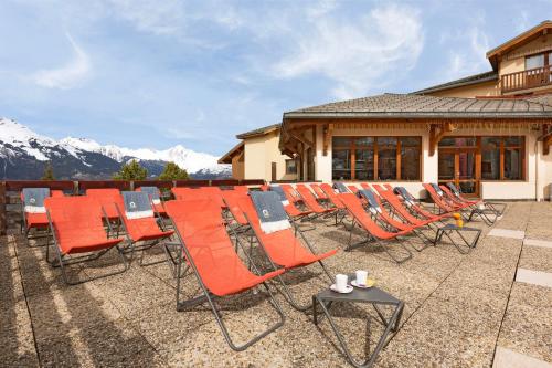 a row of chairs and tables on a patio with mountains at SOWELL Family La Lauzière in Aime La Plagne