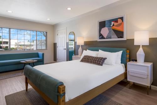 a bedroom with a large bed and a blue couch at Signature Inn Oakland in Oakland