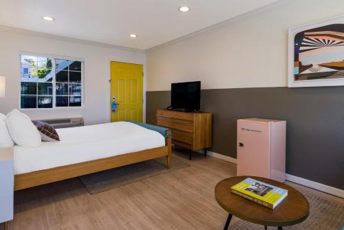 a bedroom with a bed and a tv and a table at Signature Inn Oakland in Oakland