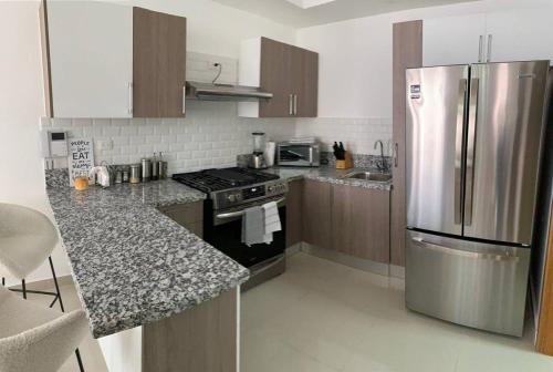 a kitchen with a stainless steel refrigerator and wooden cabinets at Lujoso PH en DT, área de trabajo y Gym, 1BR in Santo Domingo