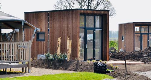 un pequeño edificio de madera con puertas de cristal en un patio en Tiny House, en Kesteren
