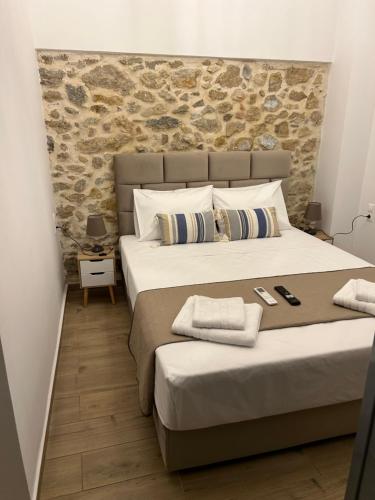 Technopolis Luxury Apartments في أثينا: غرفة نوم بسريرين وجدار حجري