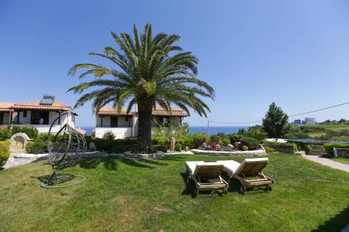 a house with two chairs and a palm tree at Porto Thea Villa in Afytos in Afitos