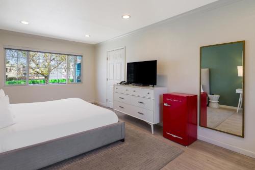 a bedroom with a bed with a red dresser and a television at Signature Inn Oakland in Oakland