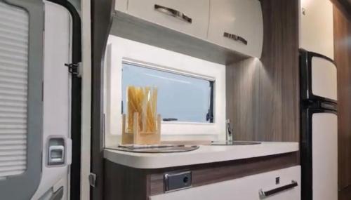 uma cozinha com um lavatório e um espelho num trailer em Portugals Infinity - AutoCaravana Luxo em Faro