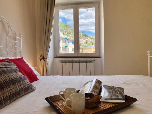bandeja con tazas de café y un libro en la cama en CasaViva - Lovely SeaView Trilo in Genova Nervi en Génova