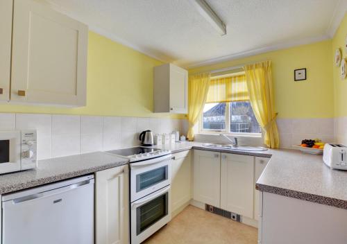 a kitchen with white appliances and a window at 20 Trail Quay Cottages in Hoveton
