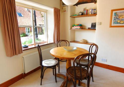 a dining room with a table and chairs and a window at Church Barn Cottage in Saxlingham
