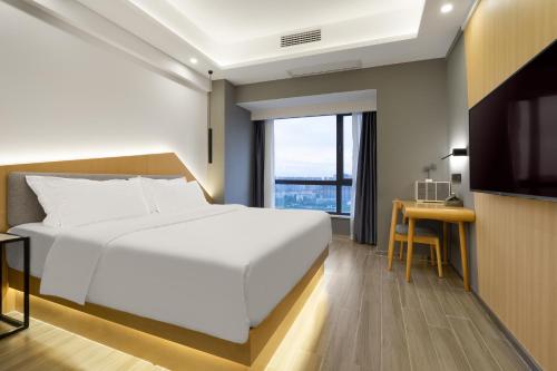 a bedroom with a large white bed and a desk at Weiming Hotel in Chengdu