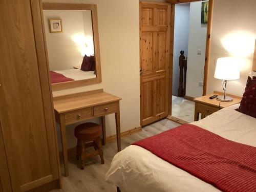 Schlafzimmer mit einem Bett und einem Schreibtisch mit einem Spiegel in der Unterkunft Abby's Cottage Roundstoneselfcatering in Roundstone