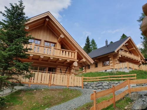 a log home with a porch and a fence at Almzauber Chalets Hochrindl in Hochrindl