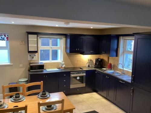 a kitchen with dark blue cabinets and a table at Abby's Cottage Roundstoneselfcatering in Roundstone