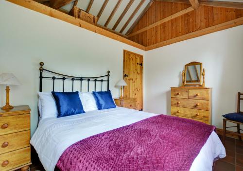 a bedroom with a large bed and a wooden ceiling at Wayfarers Cottage in Mattishall