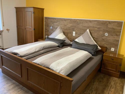 a large wooden bed with two pillows on it at Pension Selzer in Antrifttal