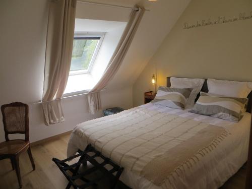 a bedroom with a large white bed with a window at Le temps d'un séjour en Bretagne Chambres d'hôtes in Nivillac