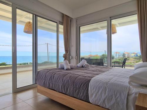 a bedroom with a bed and large glass windows at Mythic Seaview Villas in Kiotari