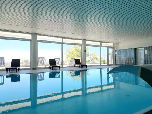 a swimming pool in a building with chairs and windows at Ferienpark Geyersberg in Freyung