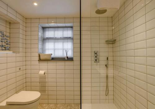 a bathroom with a toilet and a glass shower at 1 Carpenters Cottages in Holt