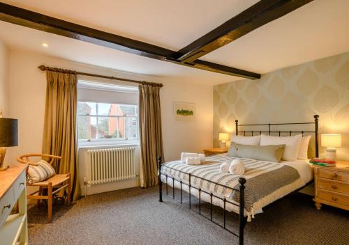 a bedroom with a large bed and a window at 1 Carpenters Cottages in Holt