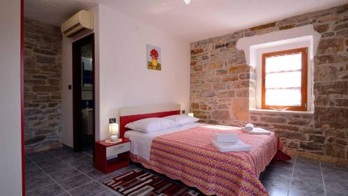 een slaapkamer met een bed en een bakstenen muur bij Estate with four stone villas and swimming pool in Buzet in Buzet