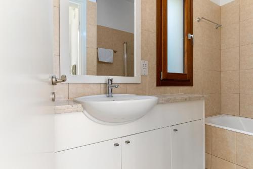 uma casa de banho com um lavatório, um espelho e uma banheira em 2 bedroom Villa Proteus with private pool, Aphrodite Hills Resort em Kouklia