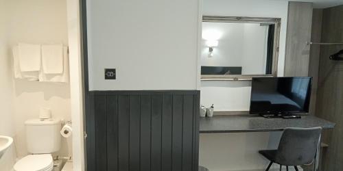 a bathroom with a toilet and a television on a counter at The Kynance House on Plymouth Hoe ,26 Ensuite Rooms in Plymouth