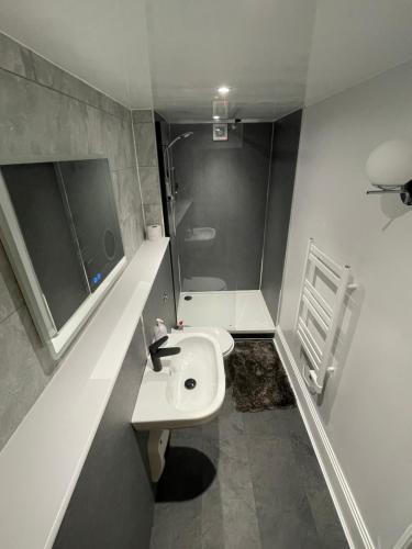 a white bathroom with a sink and a shower at Strand Suites in Douglas