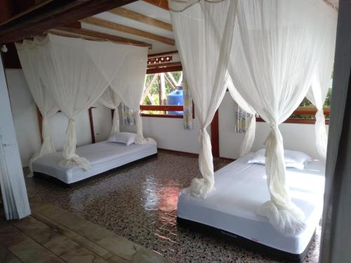 two beds in a room with white curtains at Mentawai Balcony in Masokut