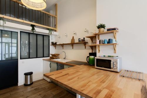 une cuisine avec une table en bois et un micro-ondes dans l'établissement Sleep in Montpellier, Molly, centre, gare, 2 ch, Tram St-Denis, à Montpellier