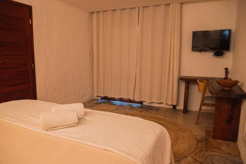 a bedroom with a white bed and a television at Moriá Eco Lodge in Icaraí