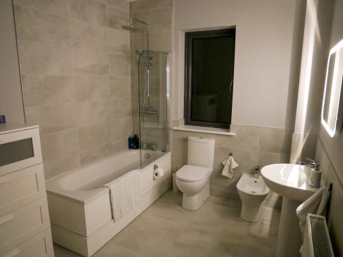 a bathroom with a tub and a toilet and a sink at Entire Modern Home with seaview and parking in Wicklow