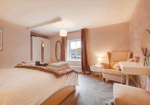 a bedroom with a large bed and a chair at 3 Pond Cottages 