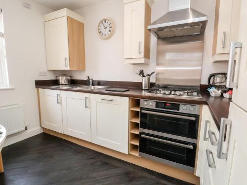 a kitchen with white cabinets and a stove top oven at 122 The Old Meadow in Shrewsbury